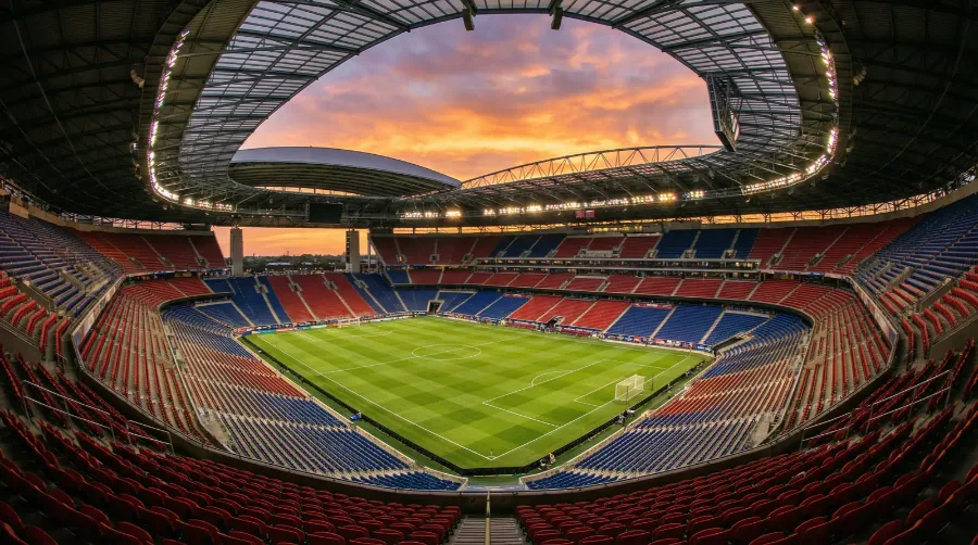 Blick auf ein modernes WM-Stadion mit Rasenfeld und Tausenden Zuschauern bei Sonnenuntergang